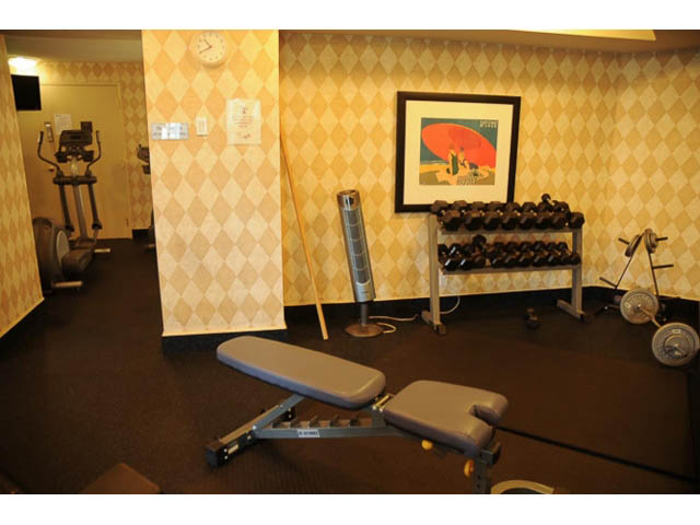 Furnished gym with workout equipment, checkered wallpaper, and framed art. - 121 -1228 Marinaside Crescent, Vancouver Downtown