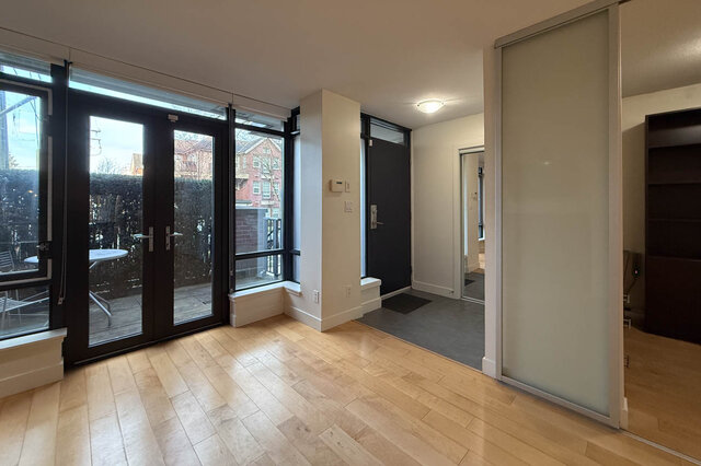 Spacious living room with hardwood floors and large sliding glass doors leading to a patio. - 3238 Tupper Street, Vancouver West Side