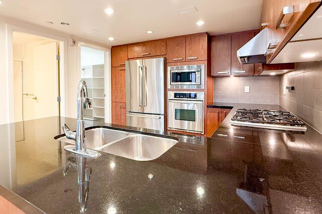 Modern kitchen with granite countertops and stainless steel appliances, featuring a sleek design and ample counter space.