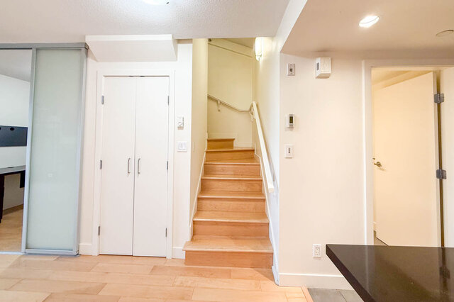 Modern entryway leading to stairs, featuring a sleek countertop and hardwood floors. - 3238 Tupper Street, Vancouver West Side