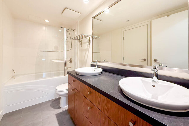 Spacious bathroom with dark countertops, modern sink, and large mirror reflecting the clean, bright space. - 3238 Tupper Street, Vancouver West Side