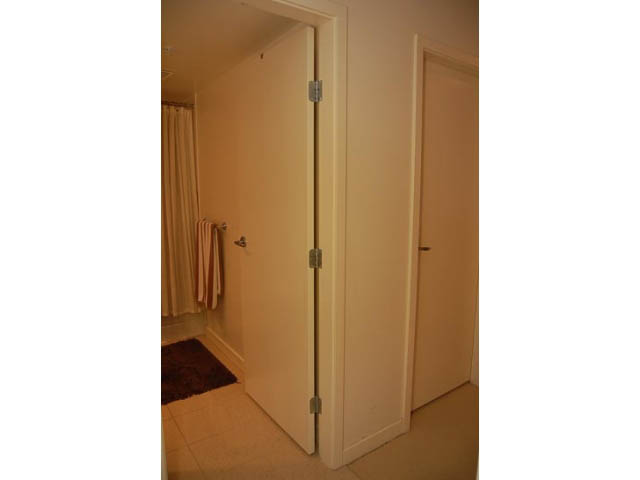 Bright den with sliding door leading to a cozy bathroom, beige walls, and a small brown rug. - 911 - 939 Expo Boulevard, Vancouver Downtown