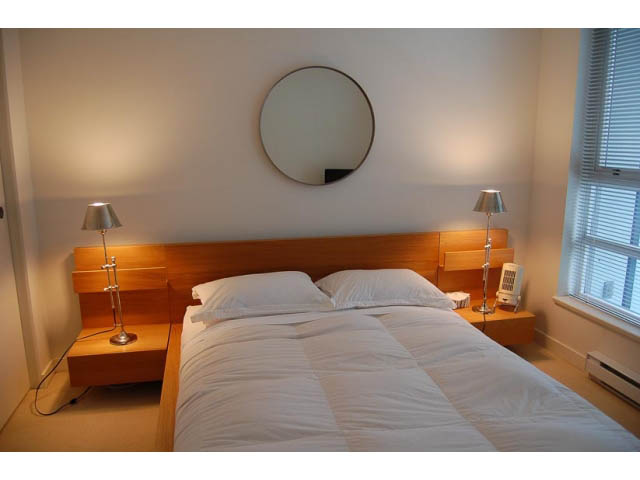 Furnished 1-bedroom + den with modern decor, wooden bedside tables, and a large mirror. - 911 - 939 Expo Boulevard, Vancouver Downtown