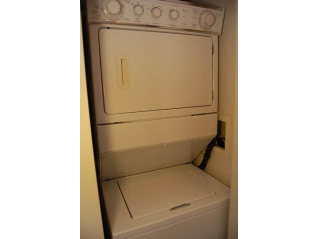 Bright laundry room with stacked washer and dryer, white cabinets. - 911 - 939 Expo Boulevard, Vancouver Downtown