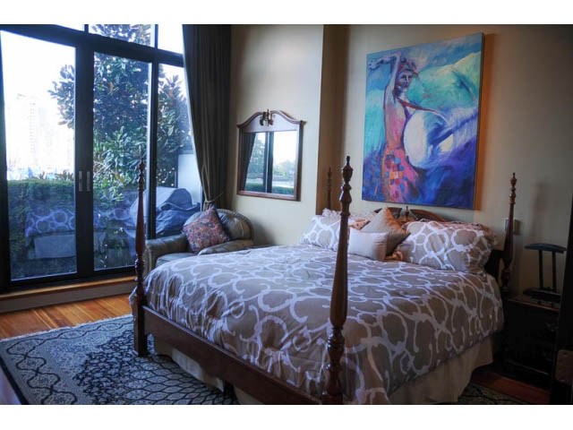 Furnished bedroom with hardwood floors, city view, and a large abstract painting on the wall. - 654 Millbank, Vancouver West Side