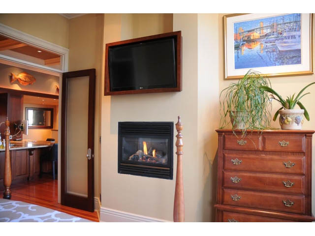 Furnished living room with hardwood floors, wall-mounted TV, and wooden dresser. - 654 Millbank, Vancouver West Side