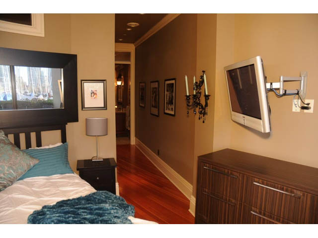 Furnished bedroom with hardwood floors, large window, and wall-mounted TV. - 654 Millbank, Vancouver West Side
