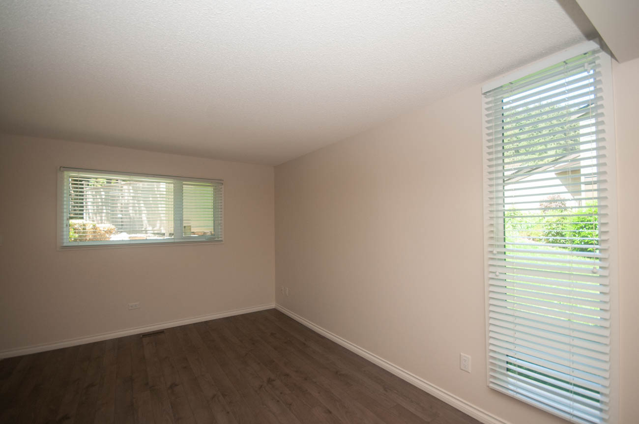 Spacious bedroom with hardwood floors and large windows letting in natural light. - 1059 Heritage Blvd, North Vancouver