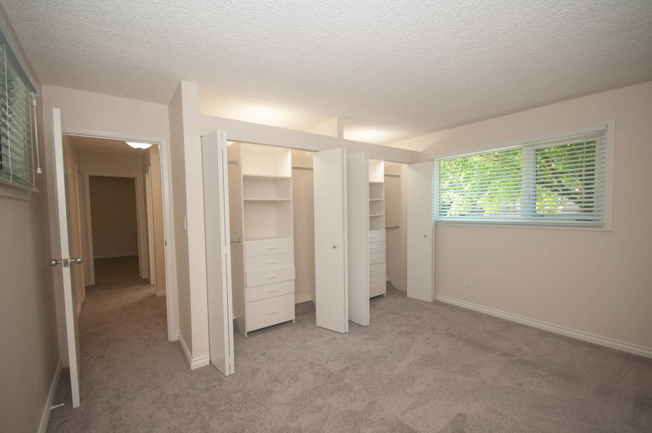 Spacious master bedroom with large walk-in closet and natural light from blinds. - 1059 Heritage Blvd, North Vancouver