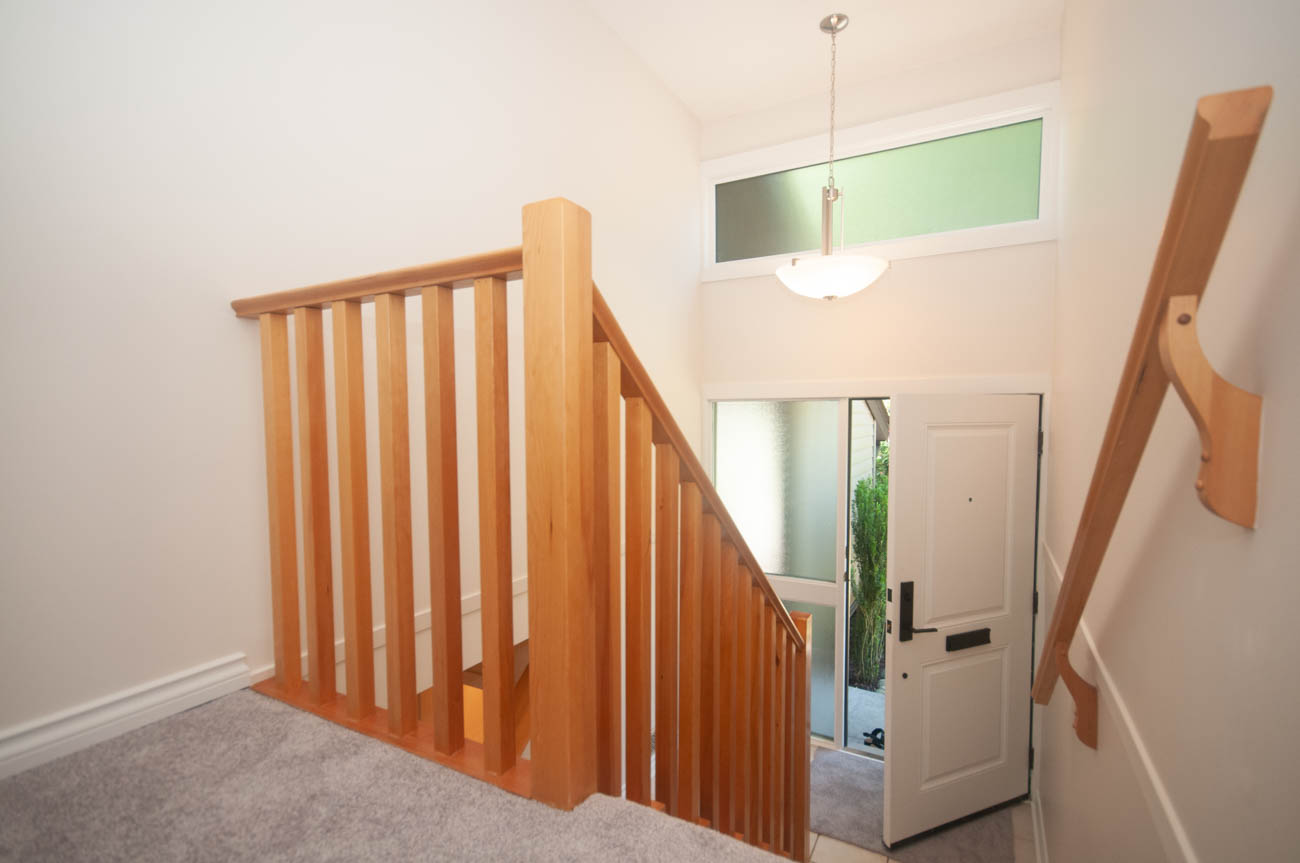 Staircase leading to upper level with wooden railings and carpeted steps. - 1059 Heritage Blvd, North Vancouver