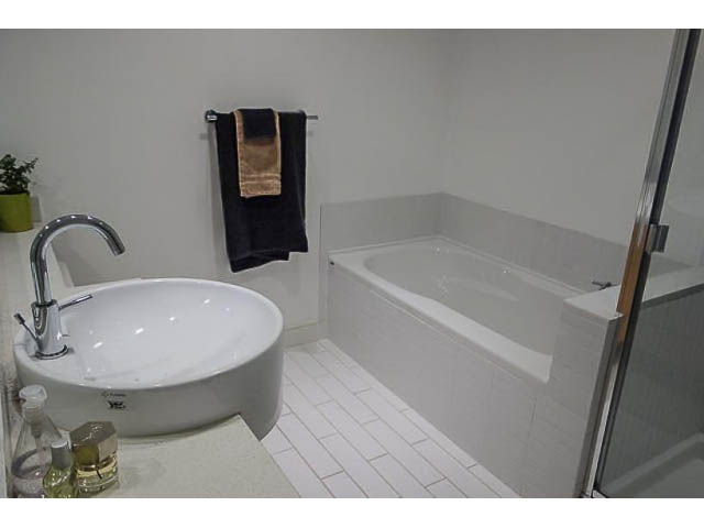 Modern bathroom with white sink, black towels, and tiled floor. - 207 - 345 Water St, Vancouver Downtown
