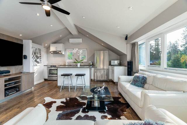 Spacious open-concept living room with hardwood floors, cowhide rug, and city view. - 420-B Tempe Crescent, North Vancouver