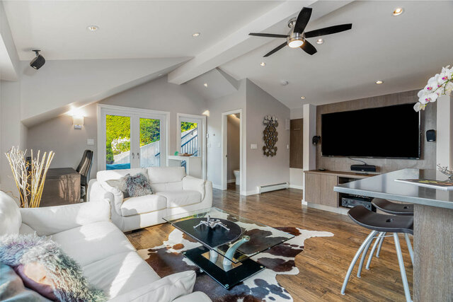 Spacious living room with hardwood floors, cowhide rug, and modern furniture. - 420-B Tempe Crescent, North Vancouver
