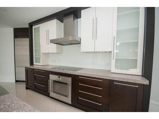 Bright kitchen with granite countertops, stainless steel appliances, and dark wood cabinets.