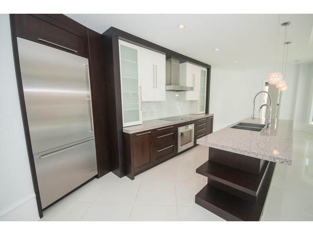 Bright kitchen with granite countertops, dark wood cabinets, and stainless steel appliances.