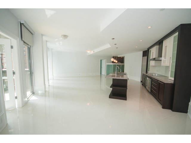 Bright kitchen with dark cabinetry and modern appliances, featuring a sleek countertop and glossy white floors.