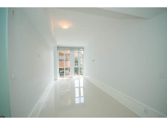 Bright hallway with white walls and glossy floor, leading to a bright living area.