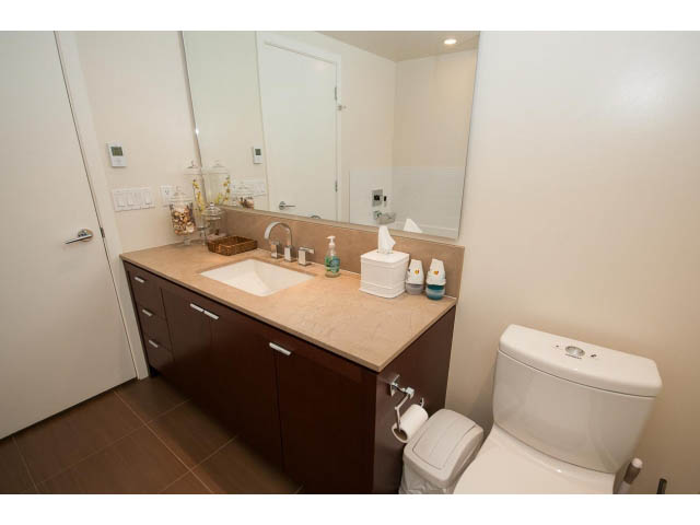 Furnished bathroom with wooden cabinets, granite countertops, and a modern sink setup. - 1606-158 West 13th Street, North Vancouver