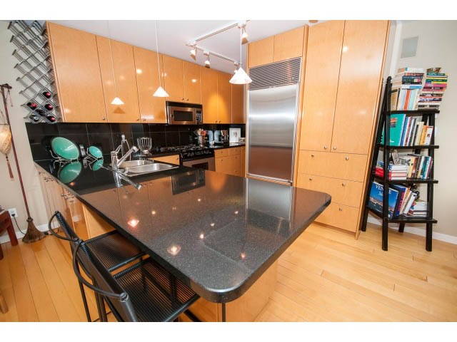 Bright kitchen with black countertops, stainless steel appliances, and hardwood floors. - 1404 - 819 Hamilton Street, Vancouver Downtown