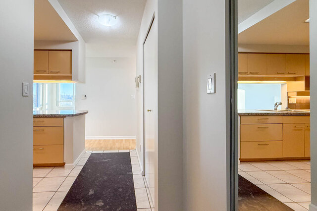 The tiled entry with a hall closet, the kitchen on both sides and hardwood floors beyond - 15B-199 Drake Street, Vancouver Downtown