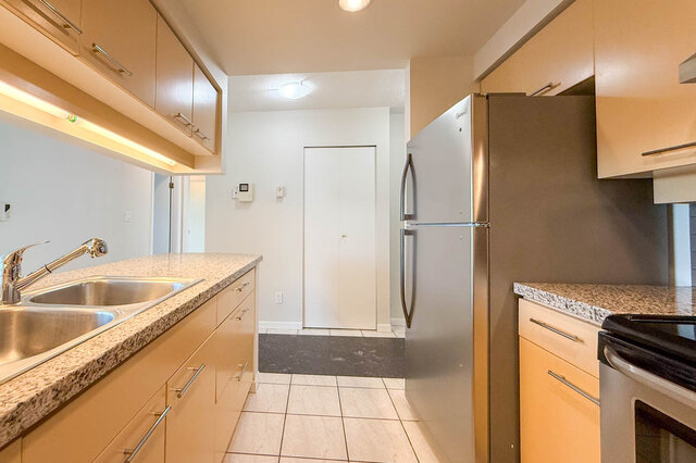 The kitchen from the sink, looking past the stainless fridge to the entry closet - 15B-199 Drake Street, Vancouver Downtown