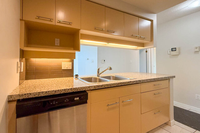 The granite counter with a double sink and stainless dishwasher below the pass-through - 15B-199 Drake Street, Vancouver Downtown