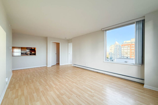The dining end of the room under a large window onto the city, with the kitchen pass-through - 15B-199 Drake Street, Vancouver Downtown