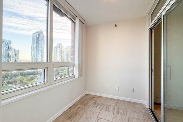 The den with a tile floor and big windows onto the towers and the park below, with sliding glass doors to a bedroom