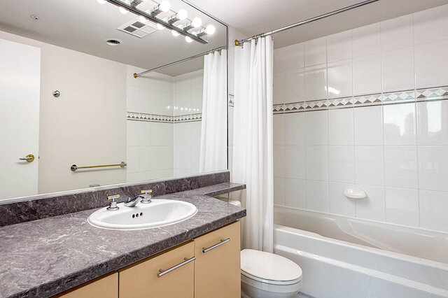 The ensuite with a tub and shower, a long vanity and a large mirror with bulb lights - 15B-199 Drake Street, Vancouver Downtown