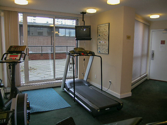 The gym's treadmill and TV by the glass doors to the patio - 15B-199 Drake Street, Vancouver Downtown