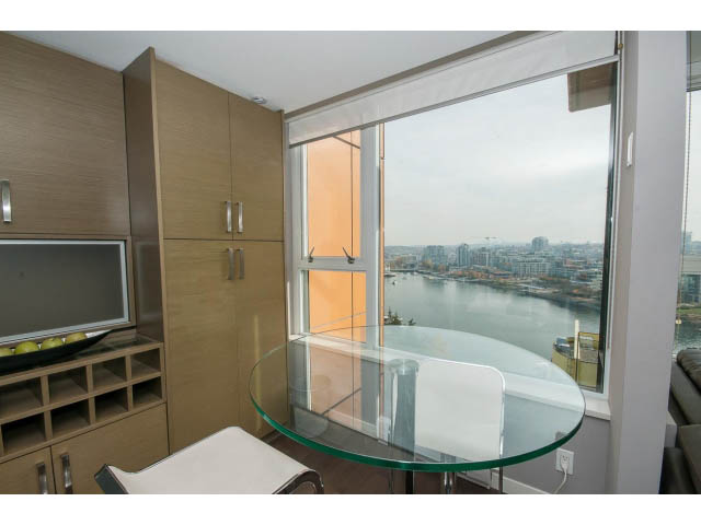 Bright dining area with a glass table and city view, modern kitchen cabinets. - 2203 - 33 Smithe Mews, Vancouver Downtown