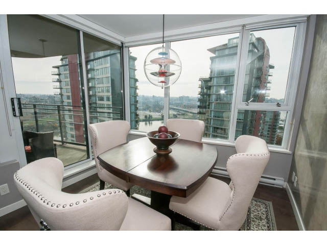 Bright dining area with a modern glass table and city view, showcasing sleek furnishings and natural light.