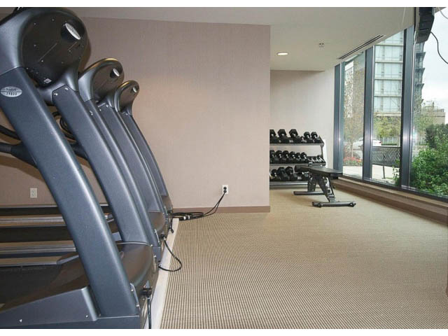 Bright gym with treadmills and dumbbells, city view through large windows. - 2203 - 33 Smithe Mews, Vancouver Downtown