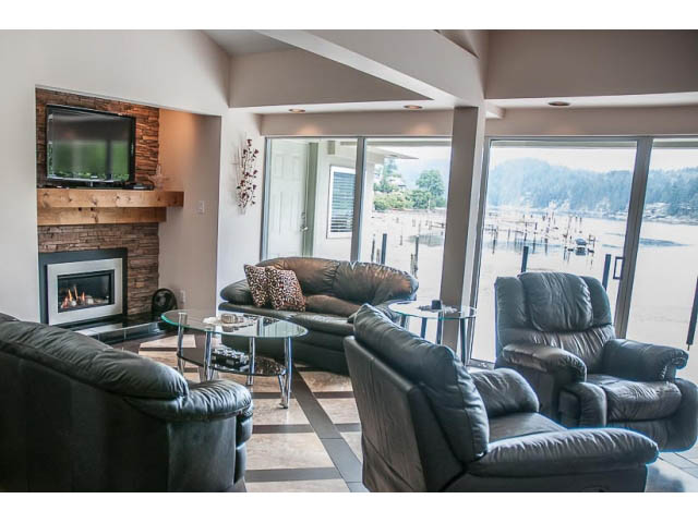 Spacious living room with fireplace, large windows, and waterfront view. - 4541 Strathcona Road, North Vancouver
