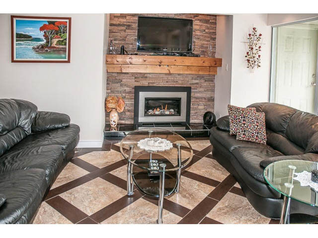 Spacious living room with a fireplace, leather couches, and a glass coffee table. - 4541 Strathcona Road, North Vancouver
