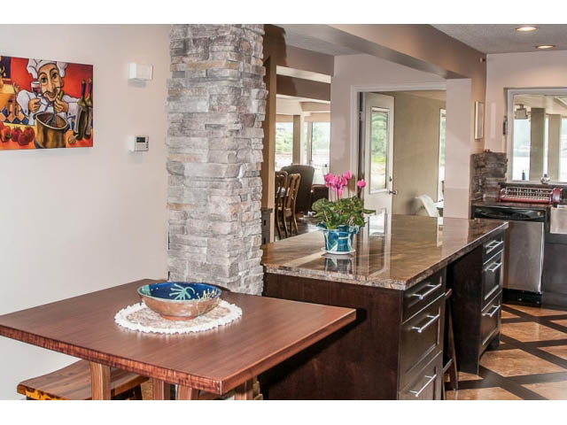 Bright kitchen with dark wood countertops, stone pillar, and hardwood floors. - 4541 Strathcona Road, North Vancouver
