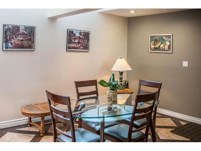 Furnished dining area with glass table, wooden chairs, and wall art. - 4541 Strathcona Road, North Vancouver