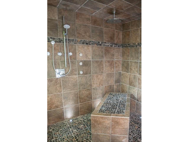 Spacious bathroom with tiled walls, rain shower, and mosaic accent. - 4541 Strathcona Road, North Vancouver