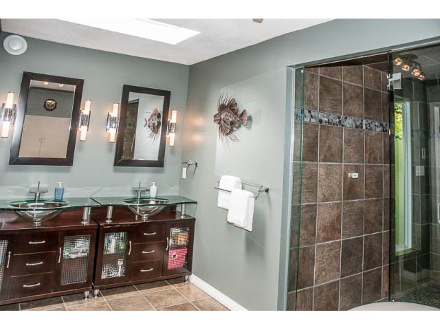 Furnished bathroom with dark wood cabinets, glass sinks, and a large walk-in shower. - 4541 Strathcona Road, North Vancouver