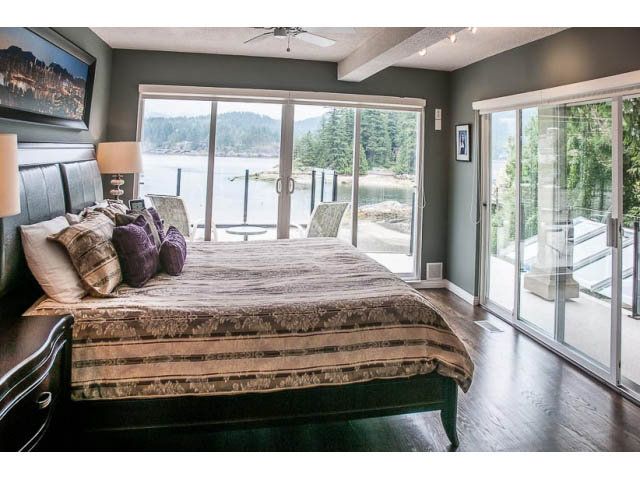 Spacious bedroom with a king bed, large windows, and a view of the water. - 4541 Strathcona Road, North Vancouver