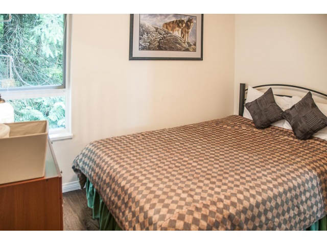 Furnished bedroom with checkered bedding and a window view of greenery. - 4541 Strathcona Road, North Vancouver