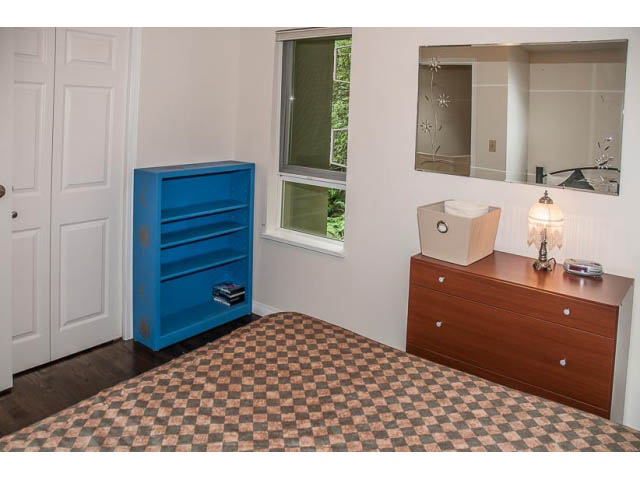 Bright bedroom with checkered bedspread, blue dresser, and large mirror. - 4541 Strathcona Road, North Vancouver