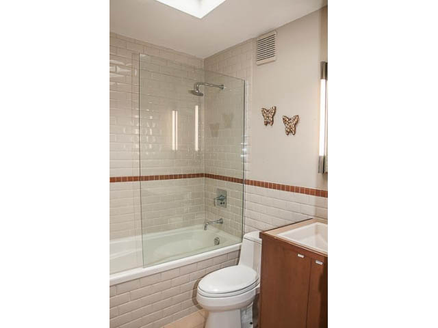 Bright bathroom with glass shower, wooden vanity, and butterfly decor. - 4541 Strathcona Road, North Vancouver
