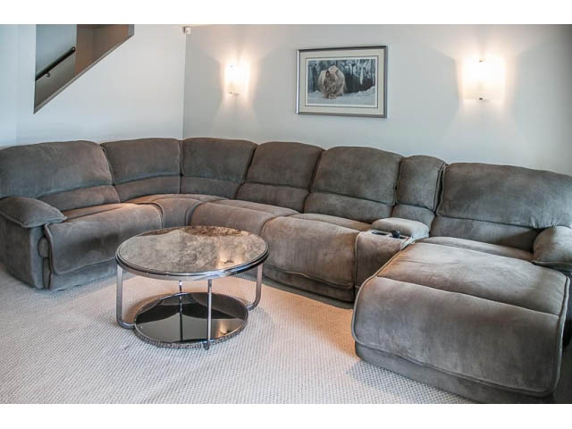 Living room with large sectional sofa, glass coffee table, and wall art. - 4541 Strathcona Road, North Vancouver