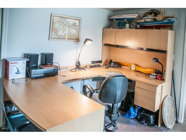 Furnished home office with wooden desk, speakers, and map on wall. - 4541 Strathcona Road, North Vancouver