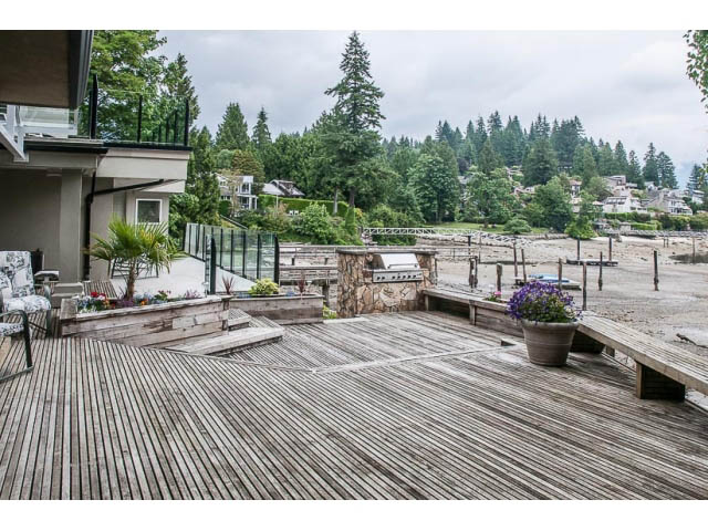 Furnished patio with wooden deck, stone accents, and garden view. - 4541 Strathcona Road, North Vancouver