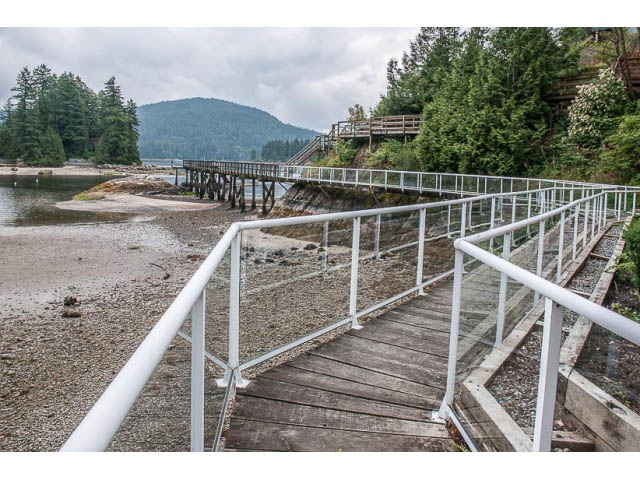 Furnished wooden walkway leading to a dock, surrounded by lush greenery and a mountain view. - 4541 Strathcona Road, North Vancouver