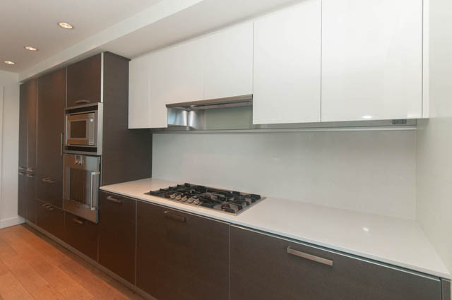 Bright kitchen with modern white cabinets, dark brown drawers, and stainless steel appliances. - 202 - 1409 W Pender St, Vancouver Downtown