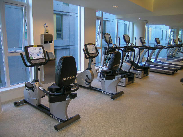 Bright fitness room with cardio machines and large windows. - 202 - 1409 W Pender St, Vancouver Downtown