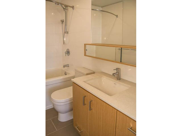 Bright bathroom with white countertop and wooden cabinets. - 501 - 221 East 3rd Street, North Vancouver